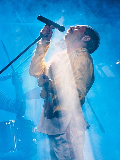 Ein Sänger steht im Rampenlicht und hält ein Mikrofon, während Nebel die Bühne umhüllt. Im Hintergrund ist ein Schlagzeuger zu sehen. | © Dunja Dopsaj