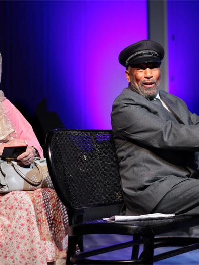 An older couple is sitting in a car. The woman is wearing a pink outfit and a veil, while the man in uniform is sitting at the wheel. | © Dietrich Dettmann