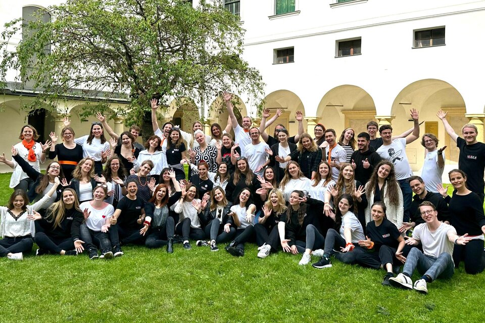 Eine große Gruppe von Menschen steht fröhlich auf einer grünen Wiese. Sie lächeln und posieren gemeinsam für ein Foto. | © Voices of Spirit – Chorverband Steiermark
