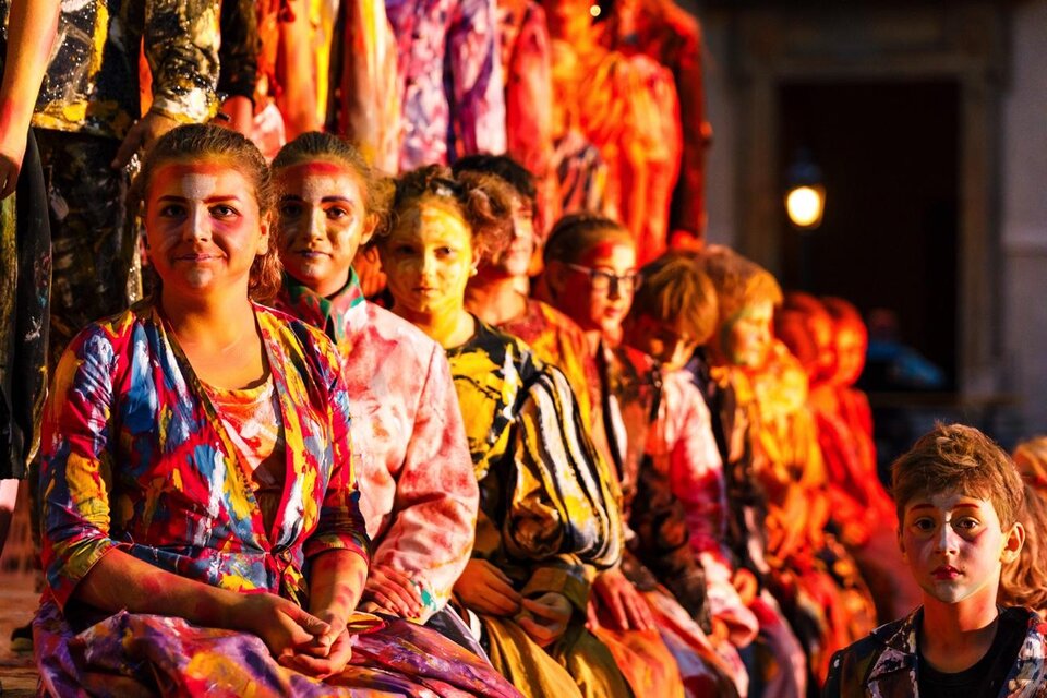 Eine Gruppe von Menschen sitzt in bunten Kleidern zusammen. Sie scheinen an einer Veranstaltung oder Aufführung teilzunehmen. | © Wandelbühne/Mediadome