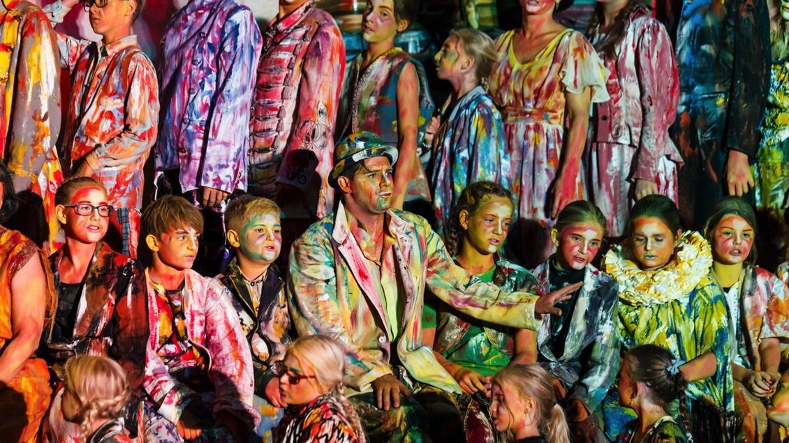 Eine Gruppe von Menschen in bunten, bemalten Kostümen steht zusammen. Sie wirken fröhlich und kreativ, umgeben von einer lebhaften Atmosphäre. | © Wandelbühne/Mediadome
