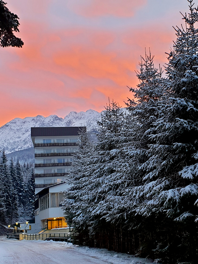 A mountain resort surrounded by snow-covered trees. The sky shines in gentle shades of pink and purple at sunset. | © Daniela Casari