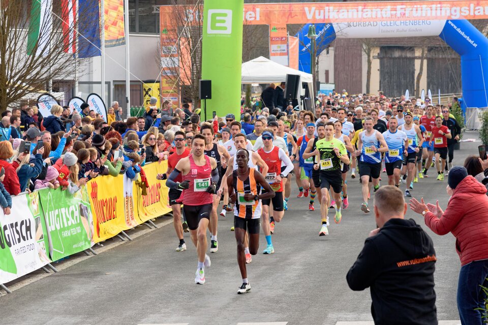 Eine große Gruppe von Läufern nimmt an einem Rennen teil. Zuschauer stehen entlang der Strecke und feuern die Teilnehmer an. | © Vulkanland Frühlingslauf