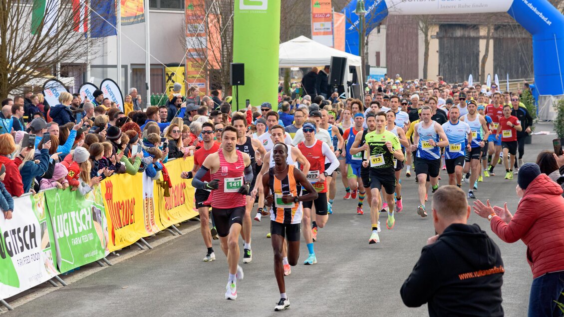 Eine große Gruppe von Läufern nimmt an einem Rennen teil. Zuschauer stehen entlang der Strecke und feuern die Teilnehmer an. | © Vulkanland Frühlingslauf