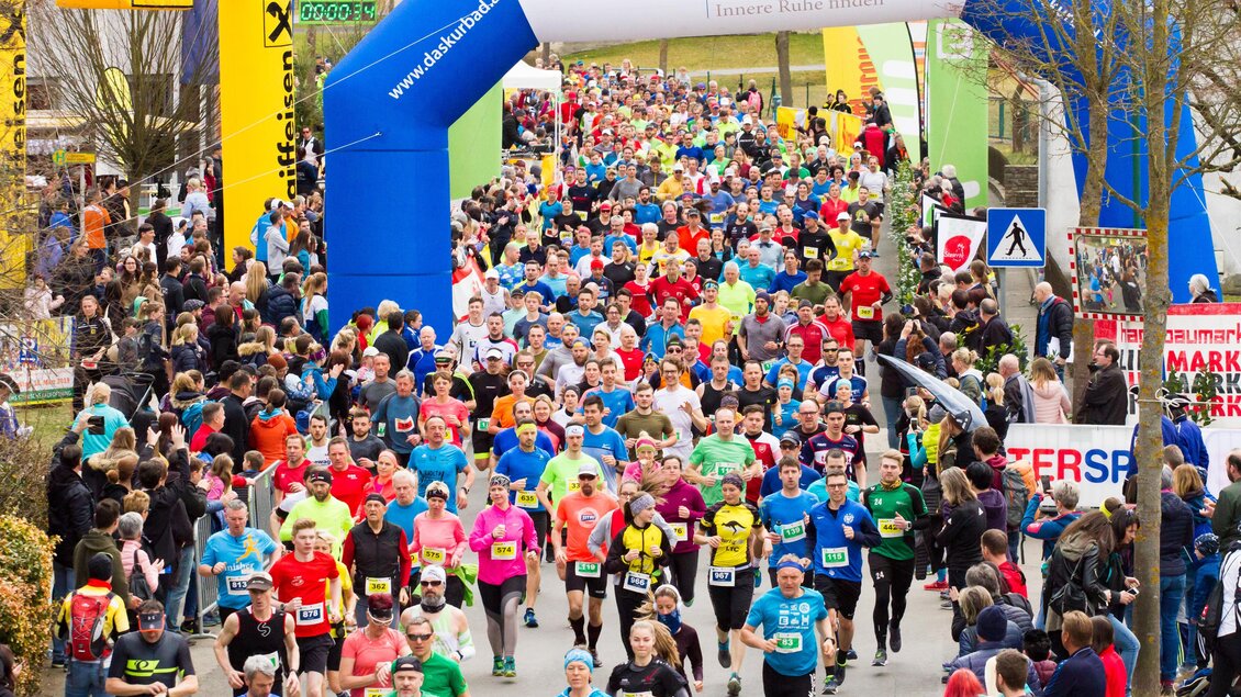Eine große Laufveranstaltung mit vielen Teilnehmern in bunten T-Shirts. Die Strecke ist von Zuschauern gesäumt und von bunten Luftballons dekoriert. | © Vulkanland Frühlingslauf