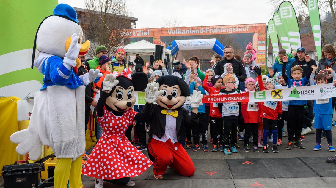 Eine fröhliche Veranstaltung mit Kindern und Maskottchen. Die Teilnehmer posieren lächelnd für ein Foto. | © Vulkanland Frühlingslauf
