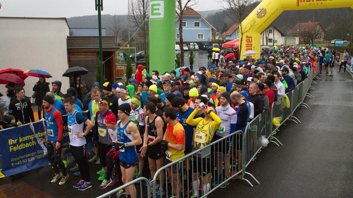 Eine große Gruppe von Läufern steht an der Startlinie eines Rennens. Es regnet, und viele Teilnehmer tragen Regenjacken und Hüte. | © ASKÖ Leitersdorf