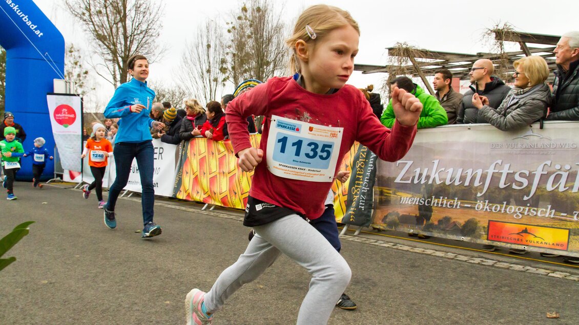 Ein Mädchen rennt schnell bei einem Sportereignis. Im Hintergrund sind Zuschauer und andere Läufer zu sehen. | © Vulkanland Frühlingslauf