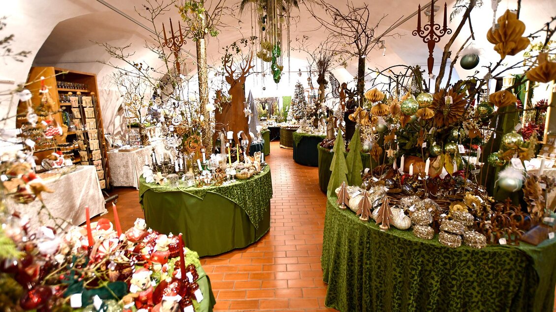 Ein wunderschöner Laden, der mit verschiedenen Dekorationen und Pflanzen geschmückt ist. Die Tische sind mit grünen Tüchern bedeckt und bieten eine Vielzahl von festlichen Artikeln an. | © Tourismusverband Thermen- & Vulkanland/Christian Thomaser