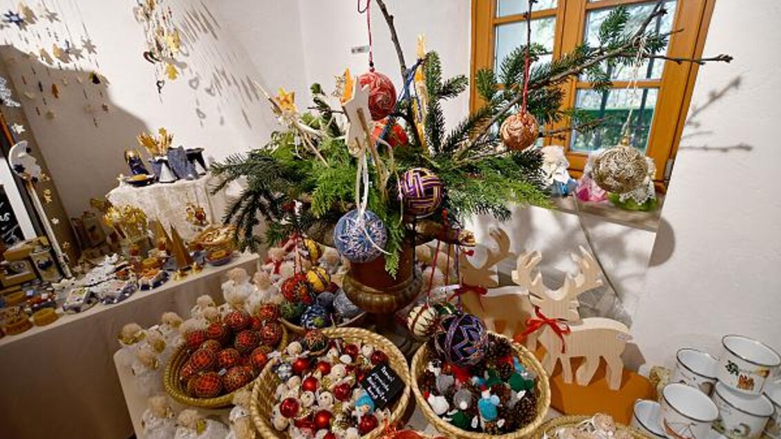 Ein festlich dekorierter Tisch mit Weihnachtsschmuck und bunten Köstlichkeiten. Im Hintergrund steht ein mit Ornamenten geschmückter Tannenbaum. | © Tourismusverband Thermen- & Vulkanland/Christian Thomaser