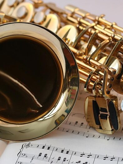 A shiny saxophone lies on a sheet of music. The musical notes are clear and legible. | © Pixapay