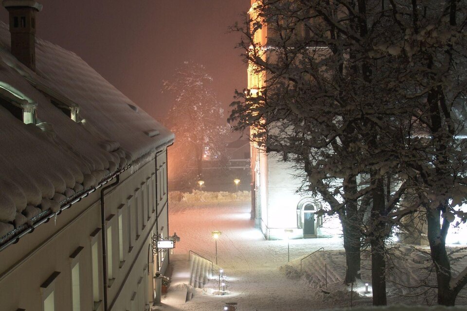 Eine stille Schneelandschaft in der Nacht, beleuchtet von sanften Lichtern. Die schneebedeckten Gebäude und Bäume schaffen eine ruhige, winterliche Atmosphäre. | © Stift Admont