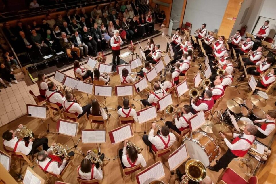 Ein großes Orchester spielt auf einer Bühne. Im Hintergrund sitzt ein Publikum und hört aufmerksam zu. | © Greith Haus