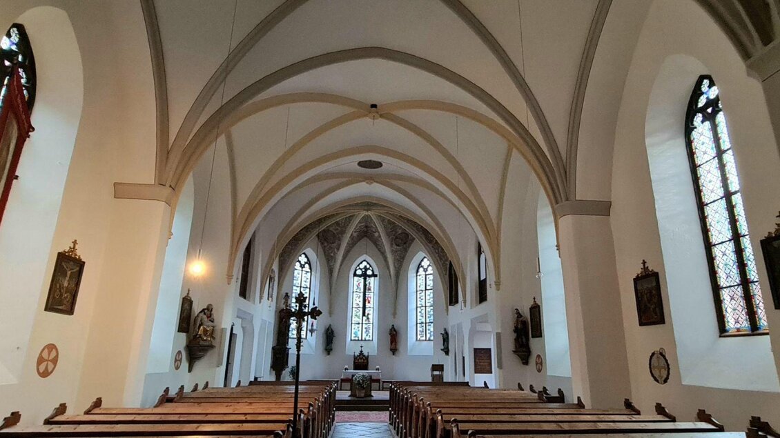 Ein schöner Kircheninnenraum mit hohen gewölbten Decken und bunten Fenstern. Bänke sind auf beiden Seiten des Raumes aufgestellt. | © Stephanie Bor