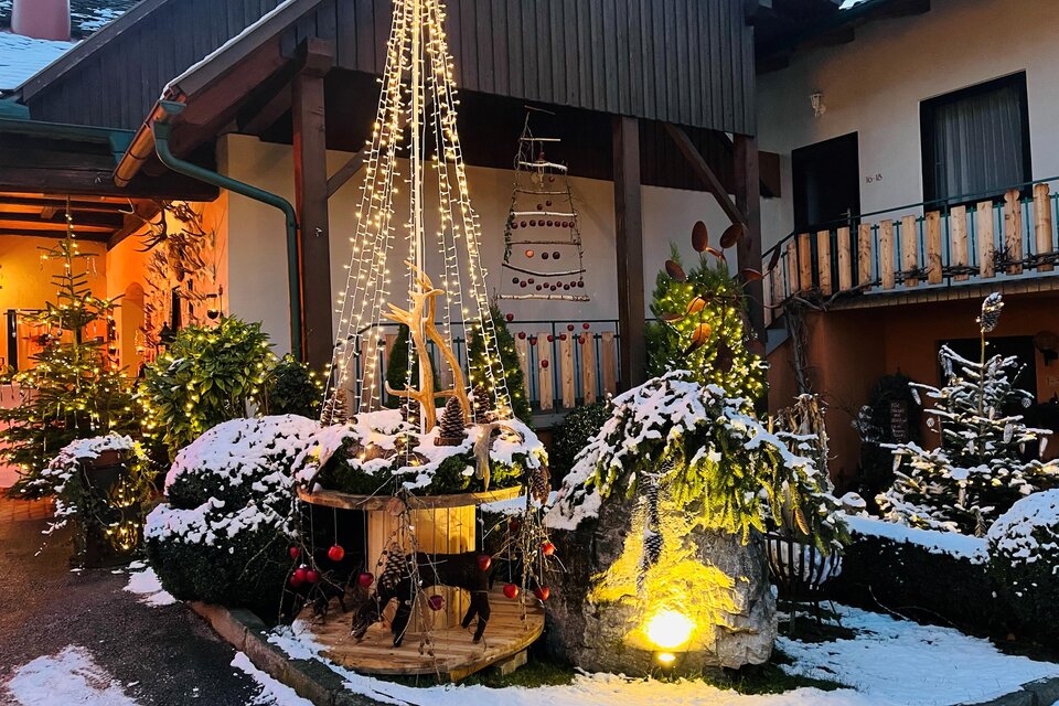 Ein festlich dekorierter Innenhof mit schneebedeckten Pflanzen. Lichterketten und Weihnachtsdekoration schaffen eine stimmungsvolle Atmosphäre. | © Wirtshaus Meißl