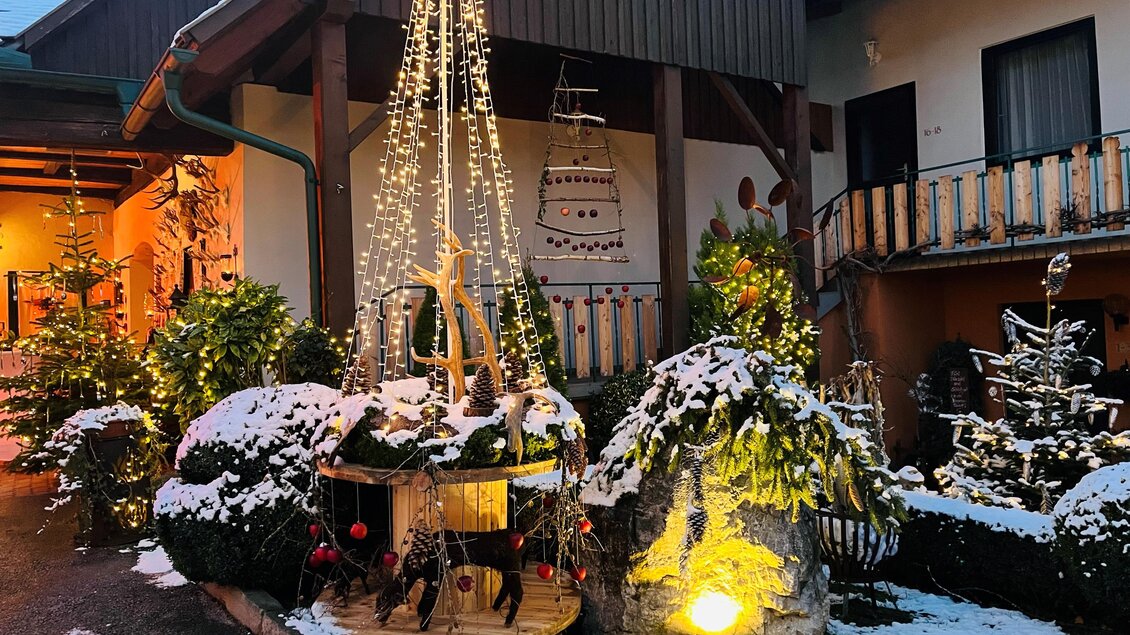 Ein festlich dekorierter Innenhof mit schneebedeckten Pflanzen. Lichterketten und Weihnachtsdekoration schaffen eine stimmungsvolle Atmosphäre. | © Wirtshaus Meißl
