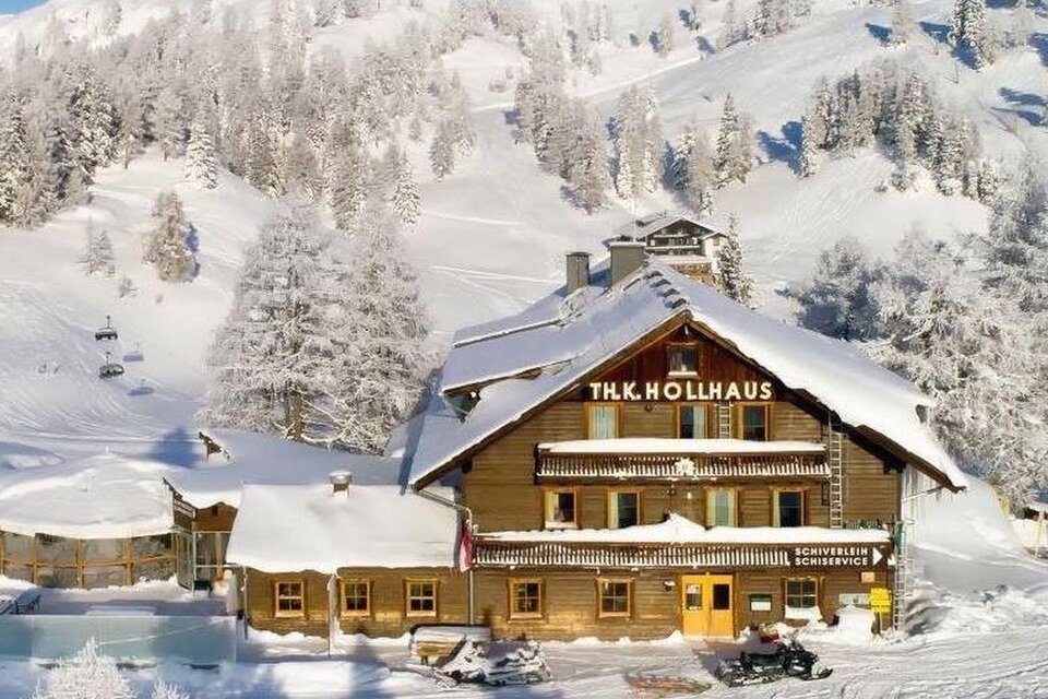 Ein charmantes Holzhaus im Winter mit Schnee bedeckt. Umgeben von einem malerischen Bergpanorama und schneebedeckten Bäumen. | © Berggasthof Hollhaus