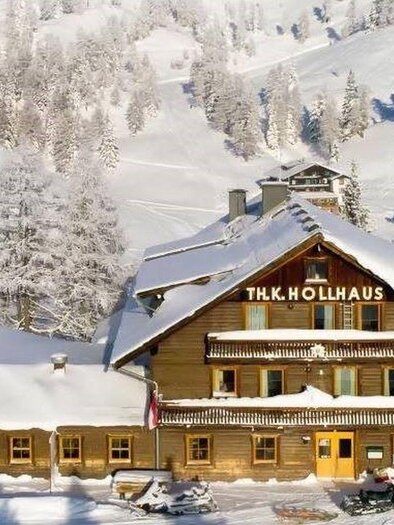 A charming wooden house covered in snow in winter. Surrounded by a picturesque mountain panorama and snow-covered trees. | © Berggasthof Hollhaus