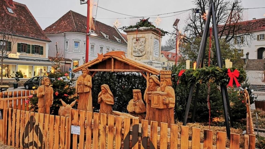 Eine festliche Krippe mit hölzernen Figuren in einer dekorierten Umgebung. Im Hintergrund sind Gebäude und Weihnachtsdekoration sichtbar. | © Oststeiermark Tourismus