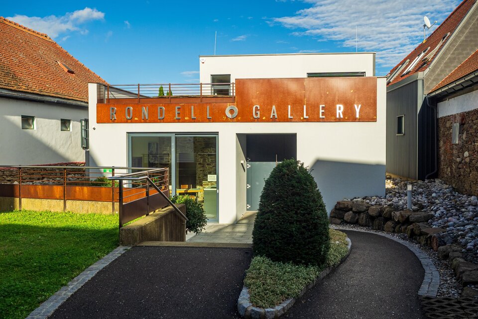 Ein modernes Galeriegebäude mit dem Schriftzug "Rondell Gallery". Umgeben von einem gepflegten Garten und einem blauen Himmel. | © TV Südsteiermark