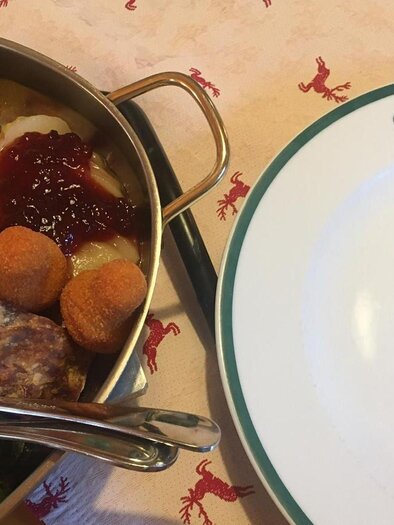 A plate with various dishes, including meat, vegetables, and side dishes. Next to it lies an empty plate with the inscription "Blaa-Alm". | © Tanja Kirchschlager