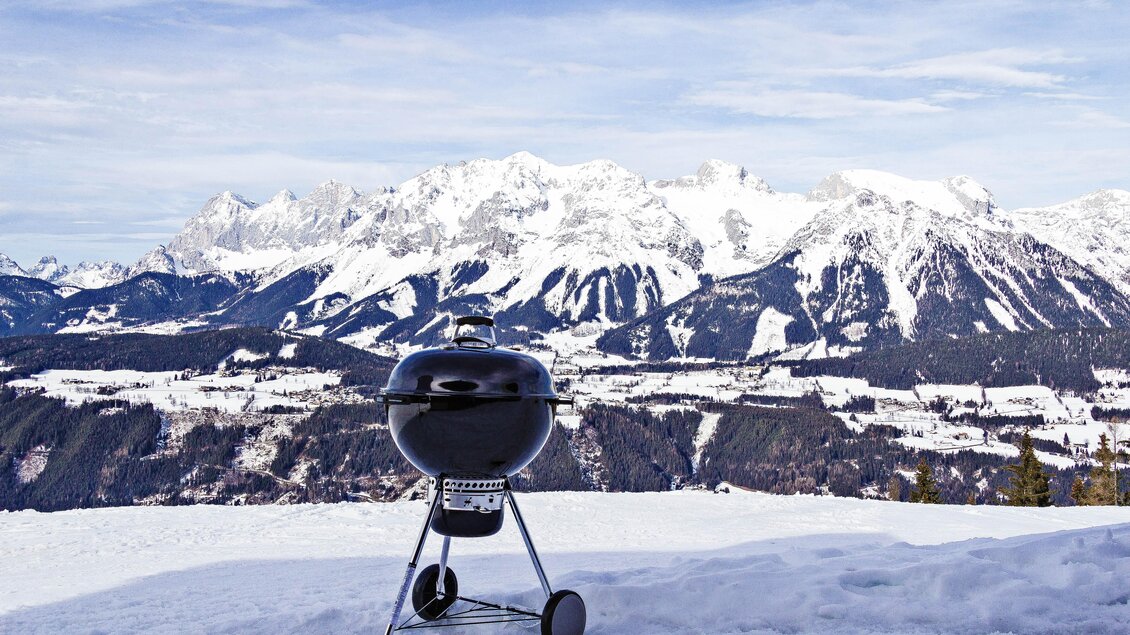 Ein Grill steht im Schnee mit einer atemberaubenden Berglandschaft im Hintergrund. Der Himmel ist klar und die Berge sind schneebedeckt. | © Christoph Buchegger