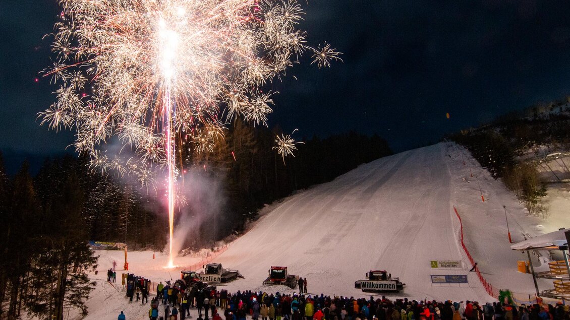 Ein beeindruckendes Feuerwerk leuchtet über einer verschneiten Piste. Viele Menschen stehen zusammen und genießen das festliche Spektakel. | © Michael Simonlehner