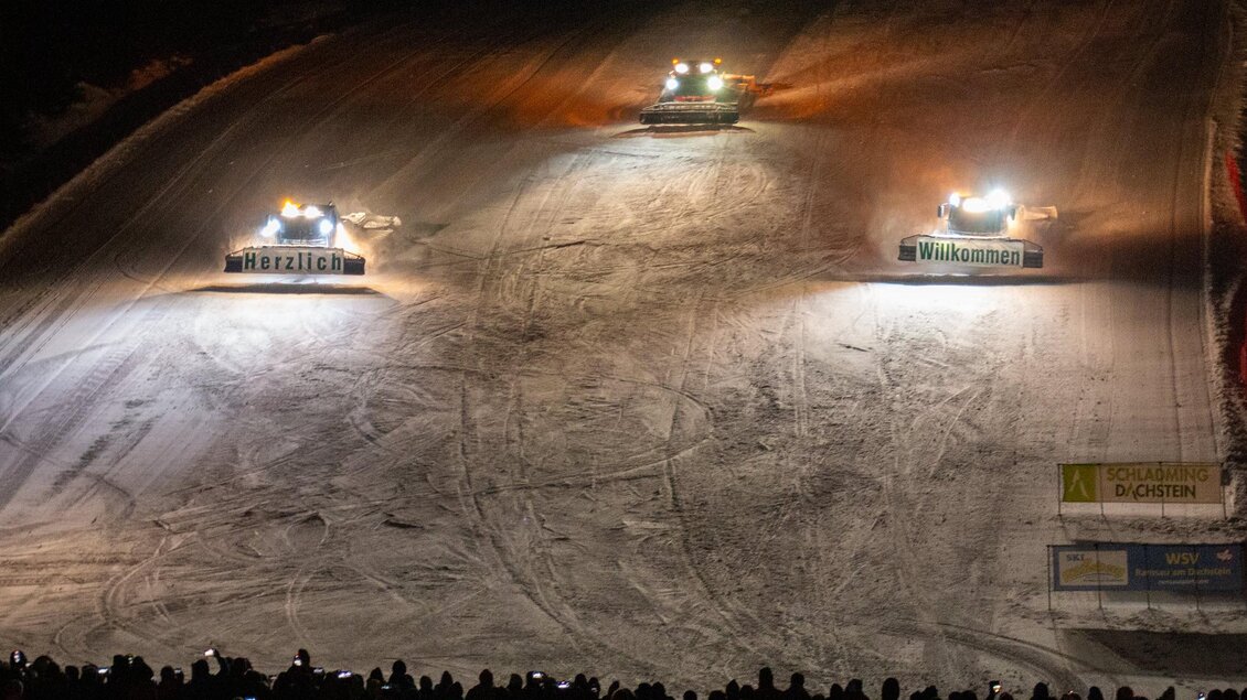 Eine winterliche Veranstaltung mit mehreren Pistenraupen, die einen beleuchteten Hang bearbeiten. Eine große Menge von Zuschauern steht unten und beobachtet das Geschehen. | © Michael Simonlehner