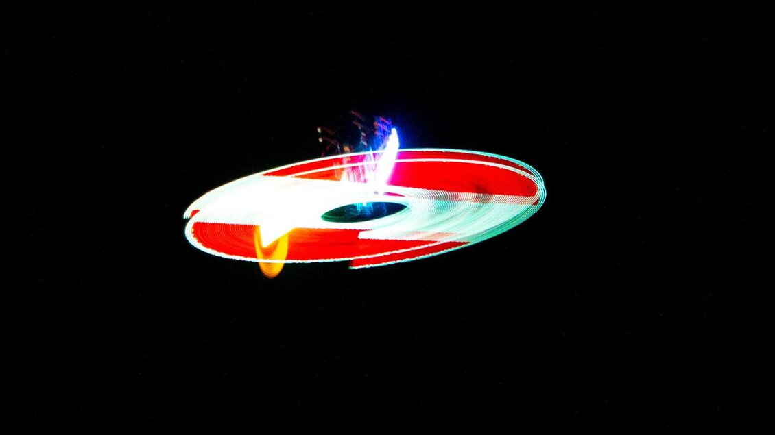 Ein kreisförmiges Lichtspiel in bunten Farben auf schwarzem Hintergrund. Die Lichter erscheinen dynamisch und kreativ. | © Michael Simonlehner