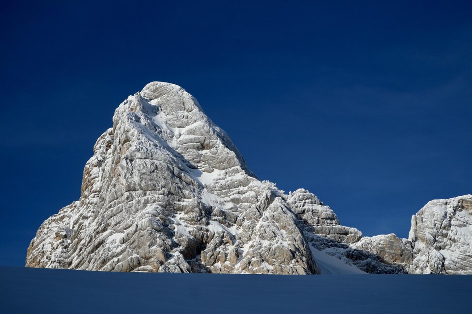 Ein majestätischer, schneebedeckter Gipfel unter einem klaren blauen Himmel. Die Felsen zeigen beeindruckende strahlenförmige Strukturen. | © Heli Rettensteiner