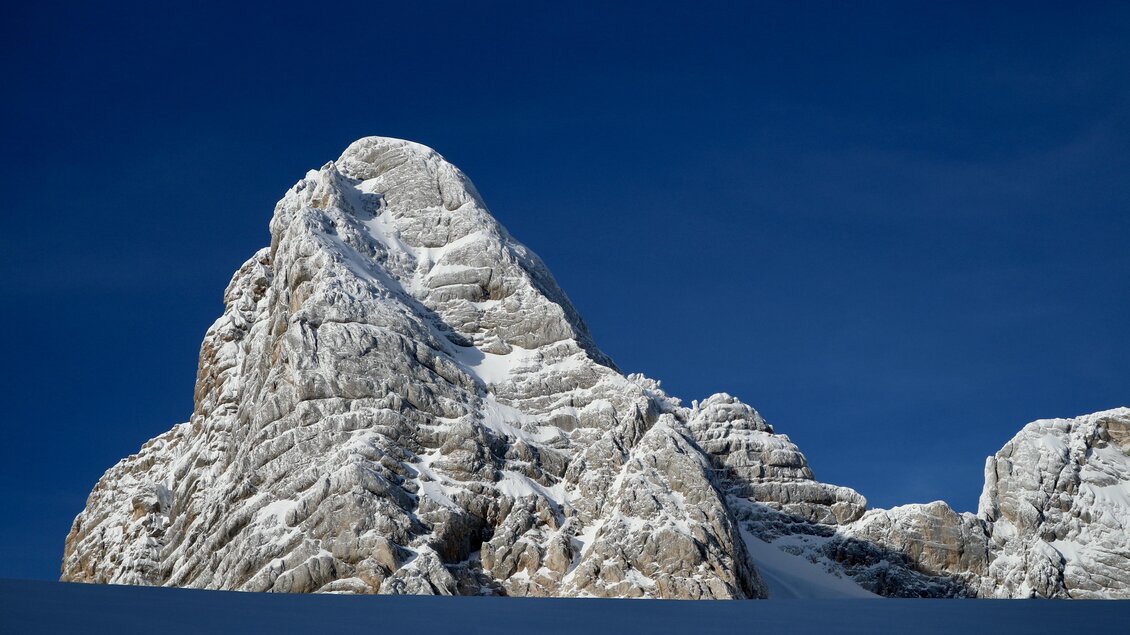 Ein majestätischer, schneebedeckter Gipfel unter einem klaren blauen Himmel. Die Felsen zeigen beeindruckende strahlenförmige Strukturen. | © Heli Rettensteiner