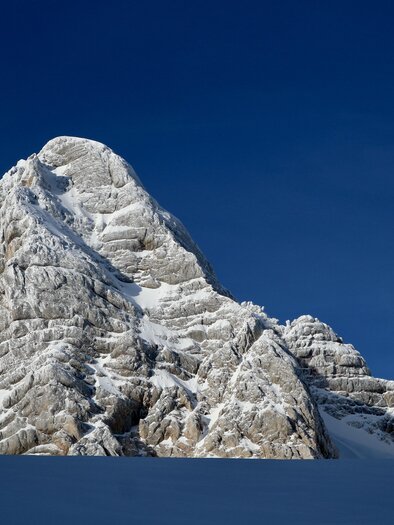 Ein majestätischer, schneebedeckter Gipfel unter einem klaren blauen Himmel. Die Felsen zeigen beeindruckende strahlenförmige Strukturen. | © Heli Rettensteiner