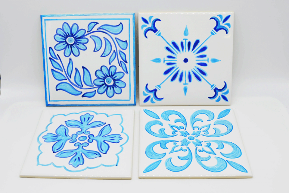 Vier dekorative Fliesen mit blauen Mustern auf weißem Grund. Jedes Design zeigt unterschiedliche florale und geometrische Motive. | ©  MuseumsCenter