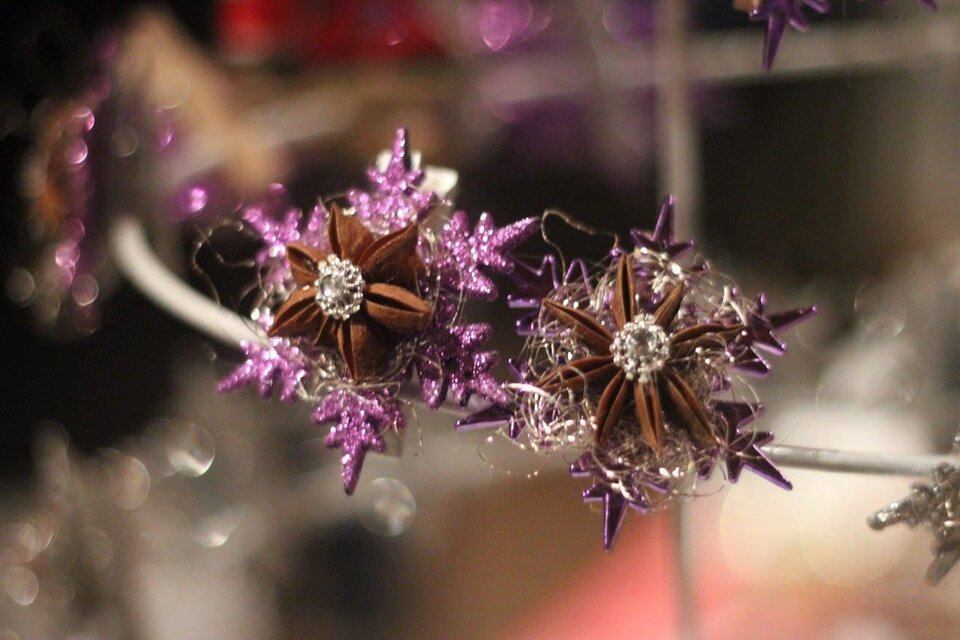 Ein dekoratives Arrangement aus lila funkeln und braunen Sternen. Die Blumen wirken verspielt und festlich.
