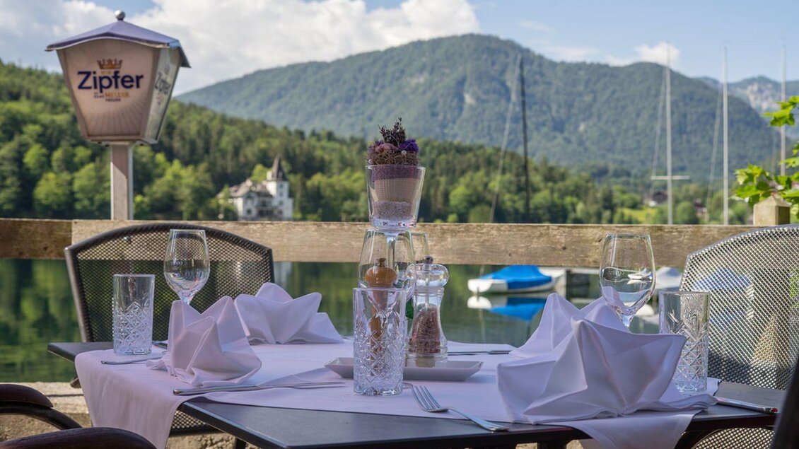 Ein schönes Restaurant mit Blick auf den See und die Berge. Der Tisch ist elegant gedeckt und lädt zum Verweilen ein. | © Gasthaus Stöckl