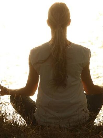 A group of alpacas is standing in a meadow. In the background, green hills and a fence can be seen. | © Anita Fössl