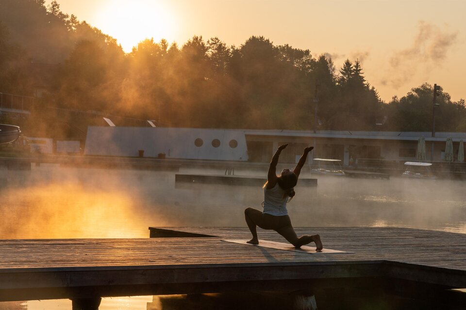 Eine Frau bei Yoga-Übung im Sonnenaufgang auf Holzsteg im Naturbad Weihermühle. | © Fuchs Sandra