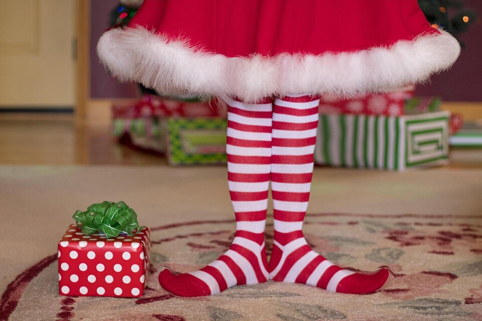 Ein Paar rot-weiß gestreifte Socken steht neben einem Geschenk. Im Hintergrund sind weihnachtlich dekorierte Geschenke zu sehen. | © Pixabay