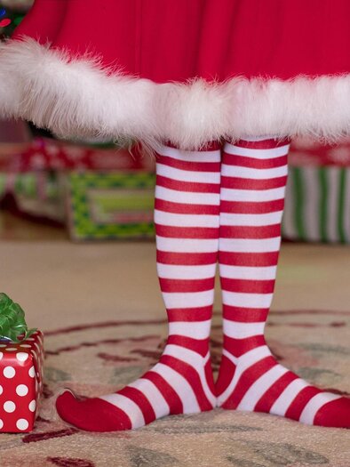 Ein Paar rot-weiß gestreifte Socken steht neben einem Geschenk. Im Hintergrund sind weihnachtlich dekorierte Geschenke zu sehen. | © Pixabay
