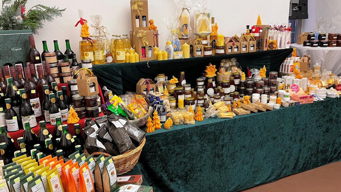 Ein bunter Marktstand mit verschiedenen Flaschen, Honig, Marmelade und Snacks. Die Waren sind ansprechend ausgestellt und laden zum Probieren ein. | © TV Thermen- & Vulkanland