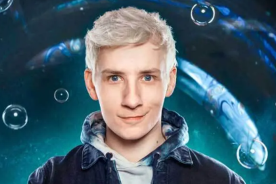 Ein junger Mann mit blonden Haaren lächelt freundlich in die Kamera. Der Hintergrund zeigt eine farbenfrohe, abstrakte Darstellung mit Blasen. | © Oststeiermark Tourismus