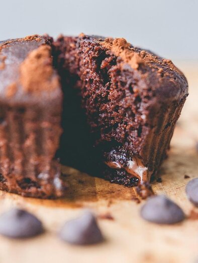 A delicious chocolate muffin, halved, reveals liquid chocolate inside. Chocolate drops are scattered all around. | © Pixabay