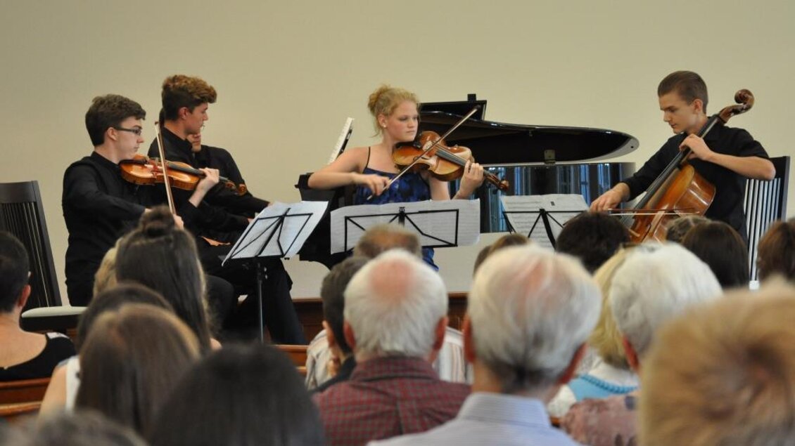 Ein Streichquartett spielt auf einer Bühne. Im Vordergrund sind die Zuhörer zu sehen, die aufmerksam lauschen. | © Kulturreferat der Marktgemeinde Irdning-Donnersbachtal