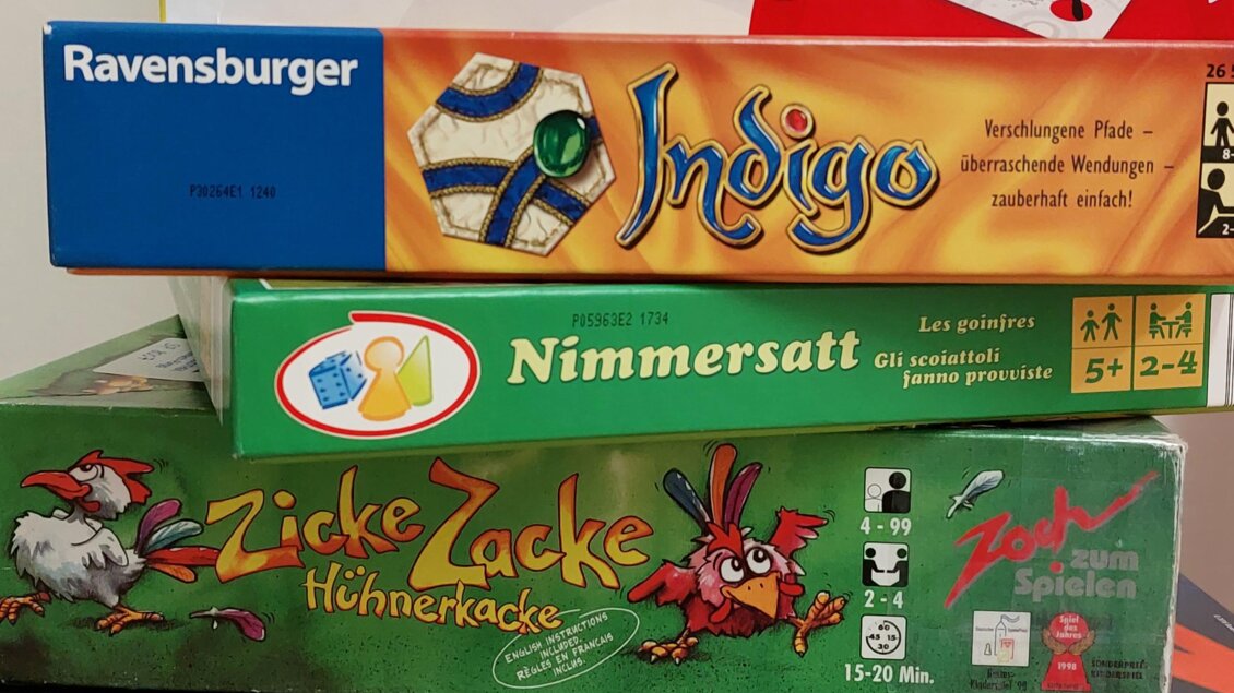 Ein Stapel von Brettspielen steht auf einem Tisch. Die Spiele sind bunt und umfassen Titel wie Twister, Indigo und Zicke Zacke. | © ÖB der MG Stainach-Pürgg