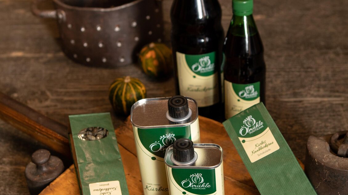 Eine Auswahl an Lebensmitteln auf einem Holzbrett. Dazu gehören Flaschen, Dosen und Verpackungen mit Kaffee und anderen Produkten.