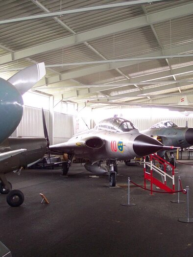 Eine Sammlung von historischen Flugzeugen in einem großen Hangar. Zu sehen sind verschiedene Flugzeugmodelle und Propeller. | © Österreichisches Luftfahrtmuseum