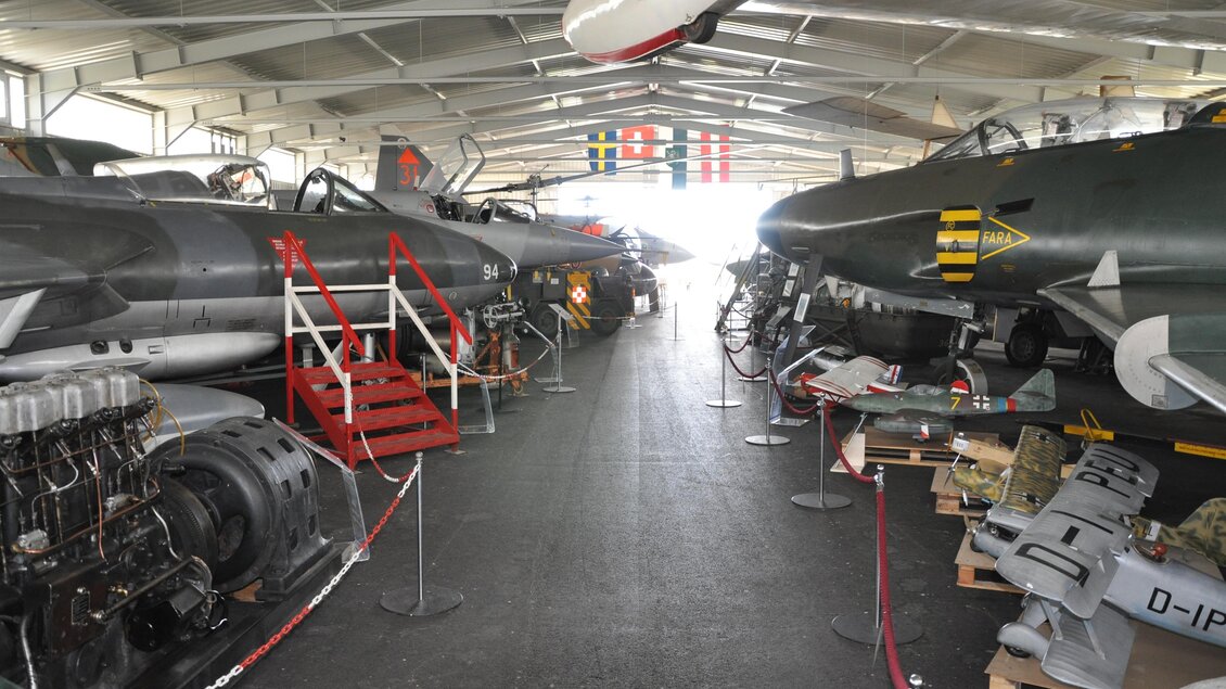 Ein Flugzeugmuseum mit mehreren historischen Flugzeugen, die in einer großen Halle ausgestellt sind. Die Umgebung ist gut beleuchtet und die Flugzeuge sind klar sichtbar. | © Österreichisches Luftfahrtmuseum