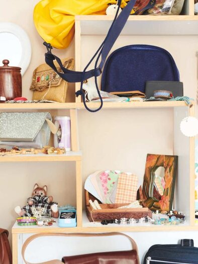 A colorful selection of accessories and bags on a shelf. Various pieces of jewelry, mirrors, and small decorative objects are also visible. | © Verein ALH