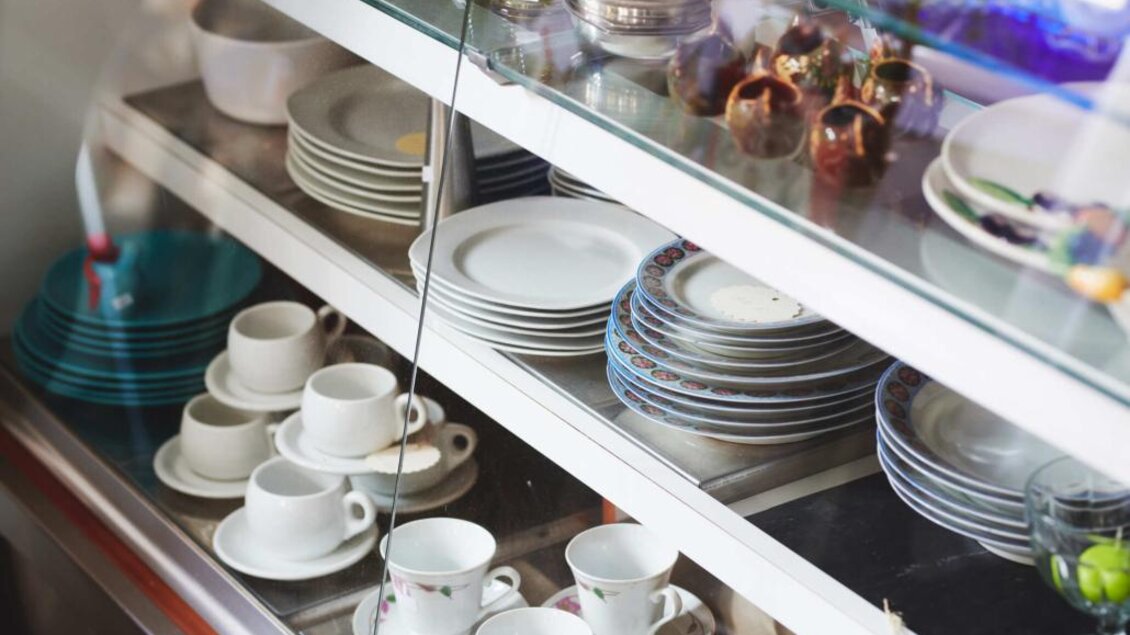 Ein Vitrinenschrank mit verschiedenen Geschirrteilen, darunter Tassen und Teller. Die Anordnung ist ordentlich und zeigt eine Mischung aus verschiedenen Designs. | © Verein ALH