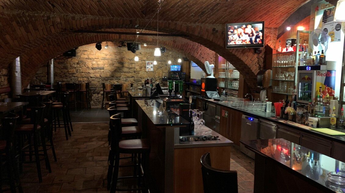 Eine gemütliche Bar im Keller mit Steinwänden und einer langen Theke. Die Atmosphäre ist einladend, mit einigen Tischen und Stühlen sowie einem Fernseher an der Wand. | © Da Nussi, facebook
